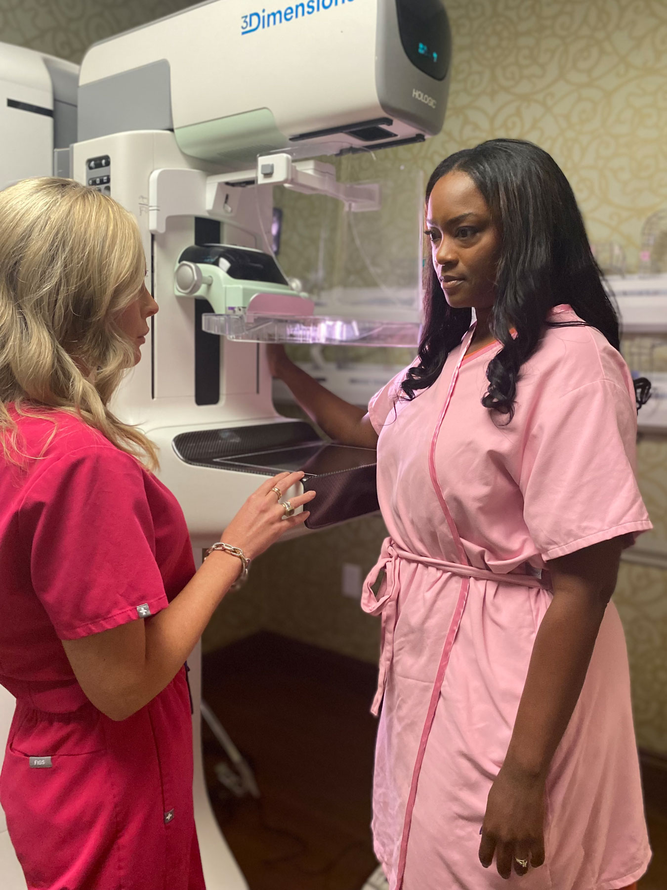 Technologist with patient before a mammogram